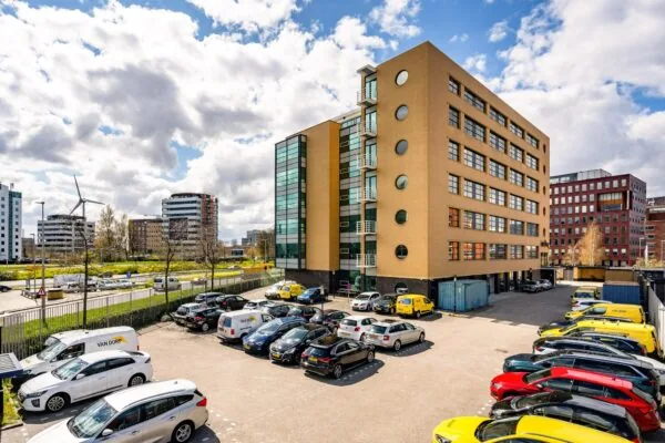 Kantoorgebouw aan de Fascinatio Boulevard met aangrenzend parkeerterrein vol auto's en bestelbussen.
